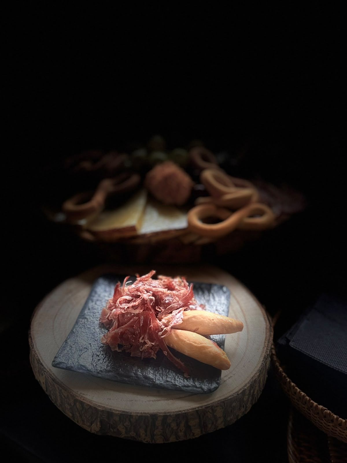 Virutas de jamón ibérico sobre pizarra con picos de pan